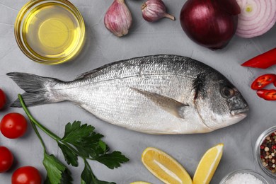 Flat lay composition with raw dorado fish and vegetables on grey table