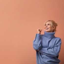 Photo of Happy woman in stylish sweater on color background. Space for text