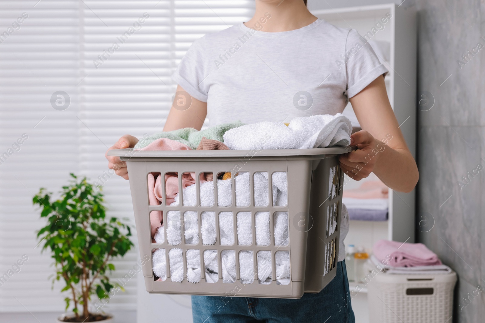 Photo of Woman with basket full of laundry in bathroom, closeup