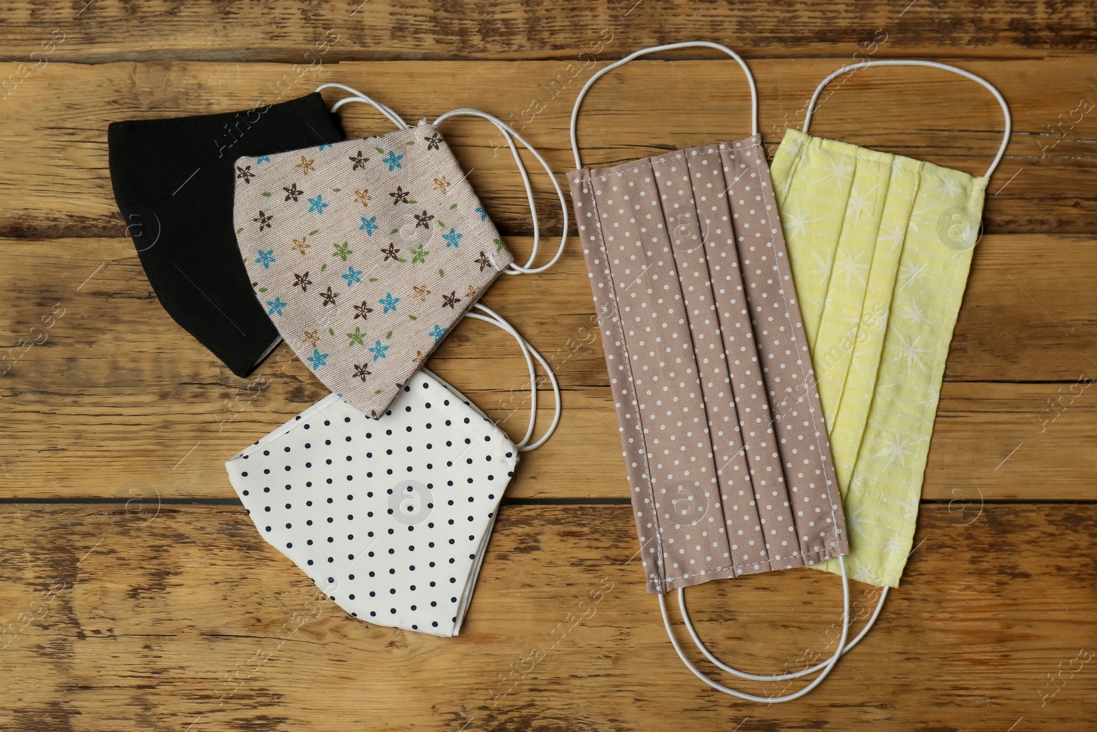 Photo of Homemade protective face masks on wooden table, flat lay