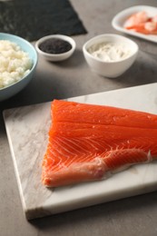 Photo of Fresh salmon and other ingredients for sushi on grey table, closeup