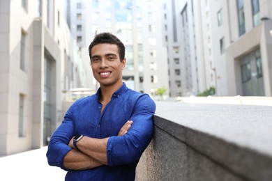 Handsome young African-American man on city street. Space for text