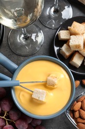 Flat lay composition with pot of tasty cheese fondue on grey table