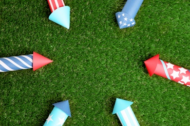 Frame of firework rockets on green grass, flat lay. Space for text