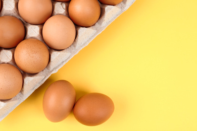 Photo of Raw chicken eggs on yellow background, flat lay
