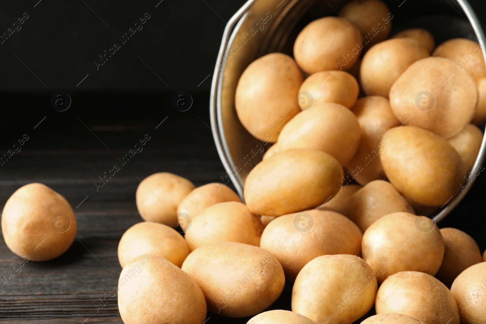 Photo of Raw fresh organic potatoes on black wooden table, closeup