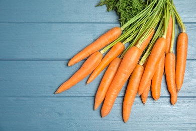 Photo of Ripe carrots on wooden background, top view