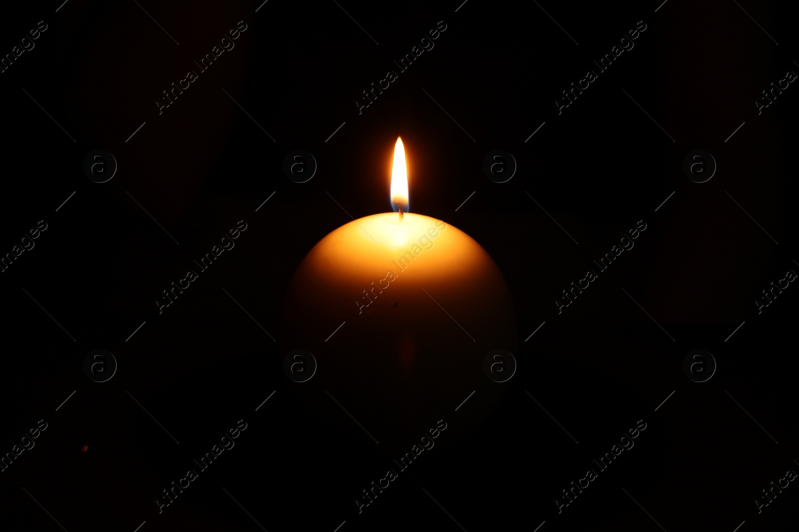 Photo of One round burning candle on black background
