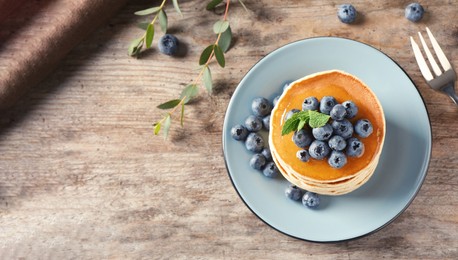 Image of Plate with pancakes and berries on wooden background, top view with space for text. Banner design