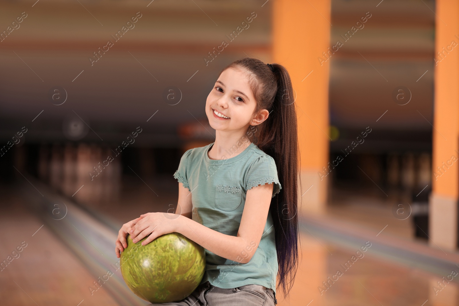 Photo of Little girl with ball in bowling club