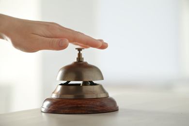 Photo of Man ringing hotel service bell at table indoors, closeup. Space for text