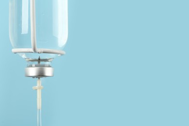 Photo of IV infusion set on light blue background, closeup. Space for text