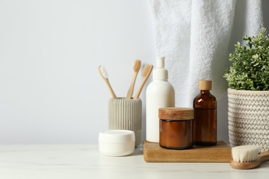 Different bath accessories and personal care products on light marble table against white wall, space for text