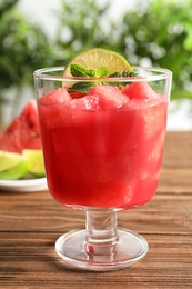 Photo of Tasty summer watermelon drink with lime and mint in glass on table