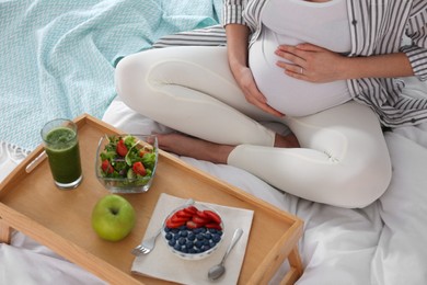 Photo of Pregnant woman with breakfast on bed, closeup. Healthy diet