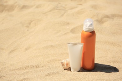 Photo of Sunscreens and seashell on sand, space for text. Sun protection care