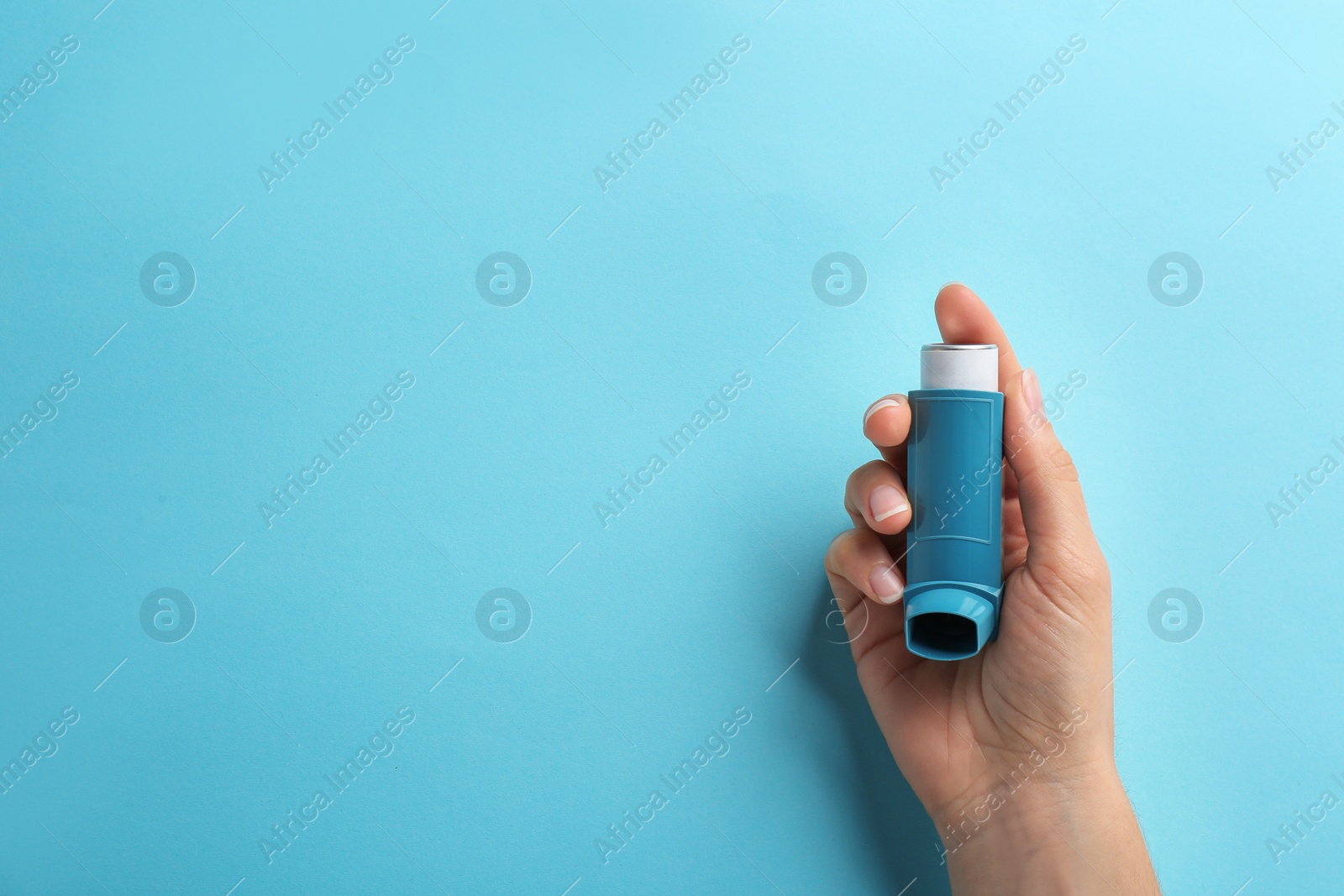 Photo of Woman holding asthma inhaler on color background, top view. Space for text