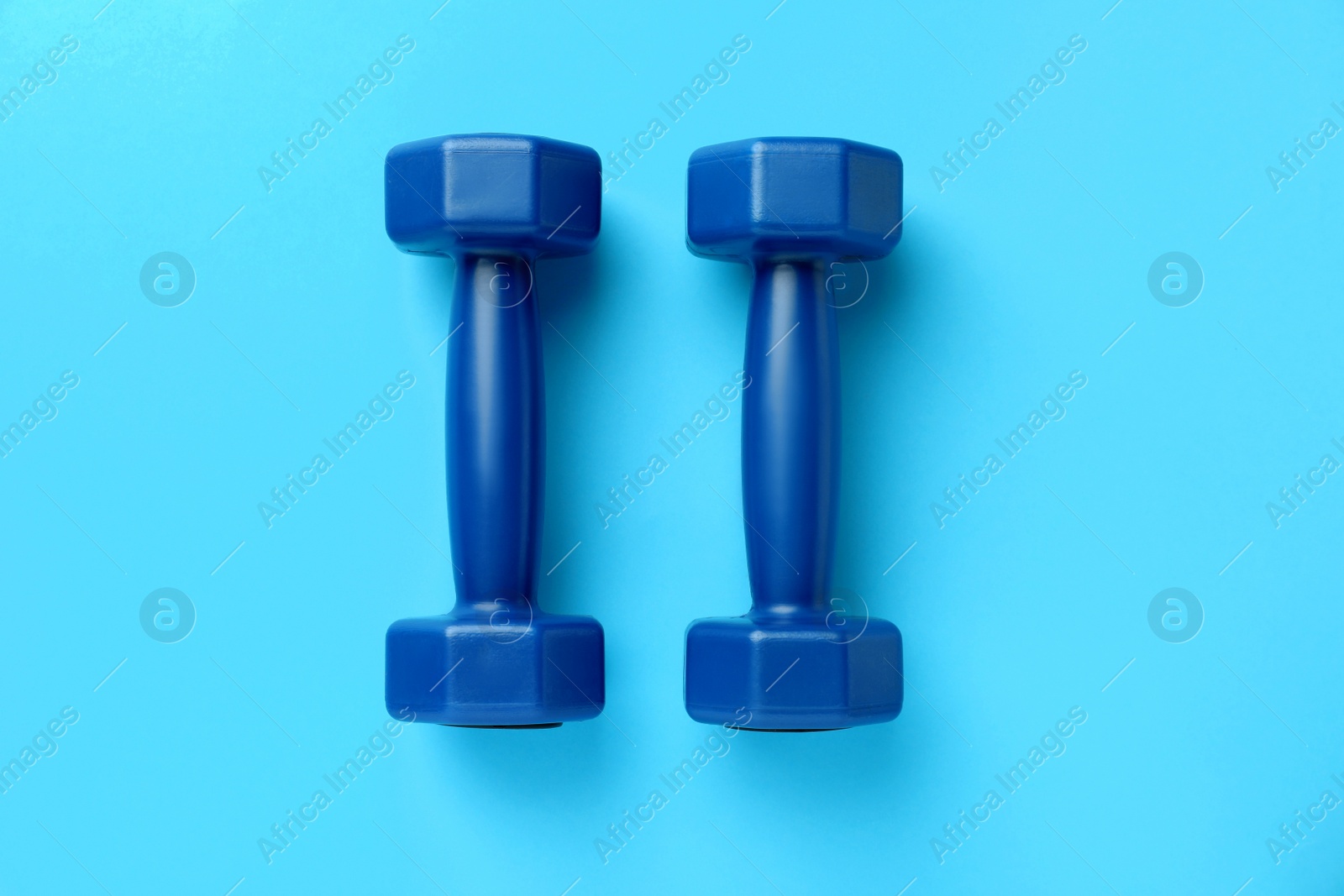 Photo of Stylish dumbbells on light blue background, flat lay
