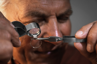 Photo of Professional jeweler evaluating beautiful ring, closeup view