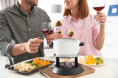 Happy couple enjoying fondue dinner at home, closeup