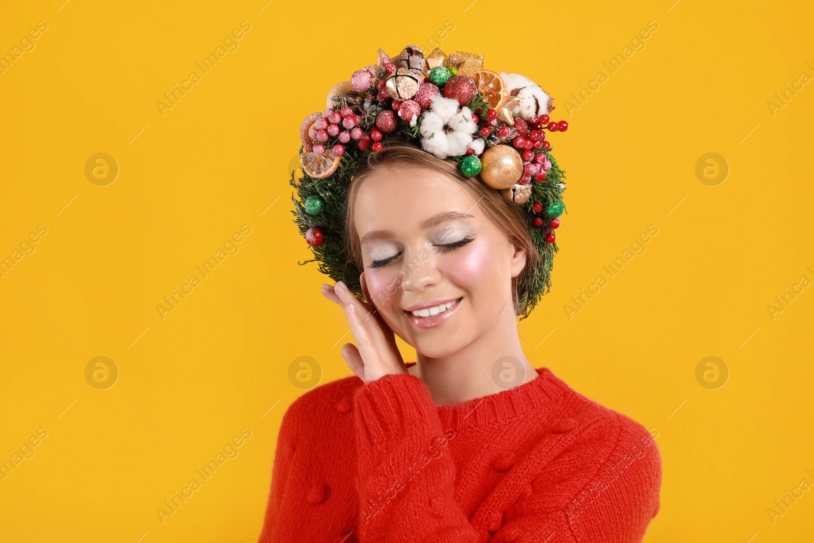 Photo of Beautiful young woman wearing Christmas wreath on yellow background