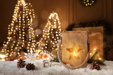 Image of Composition with wooden Christmas lantern on snow in decorated room 