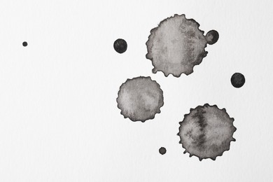 Photo of Blots of black ink on white background, flat lay. Space for text