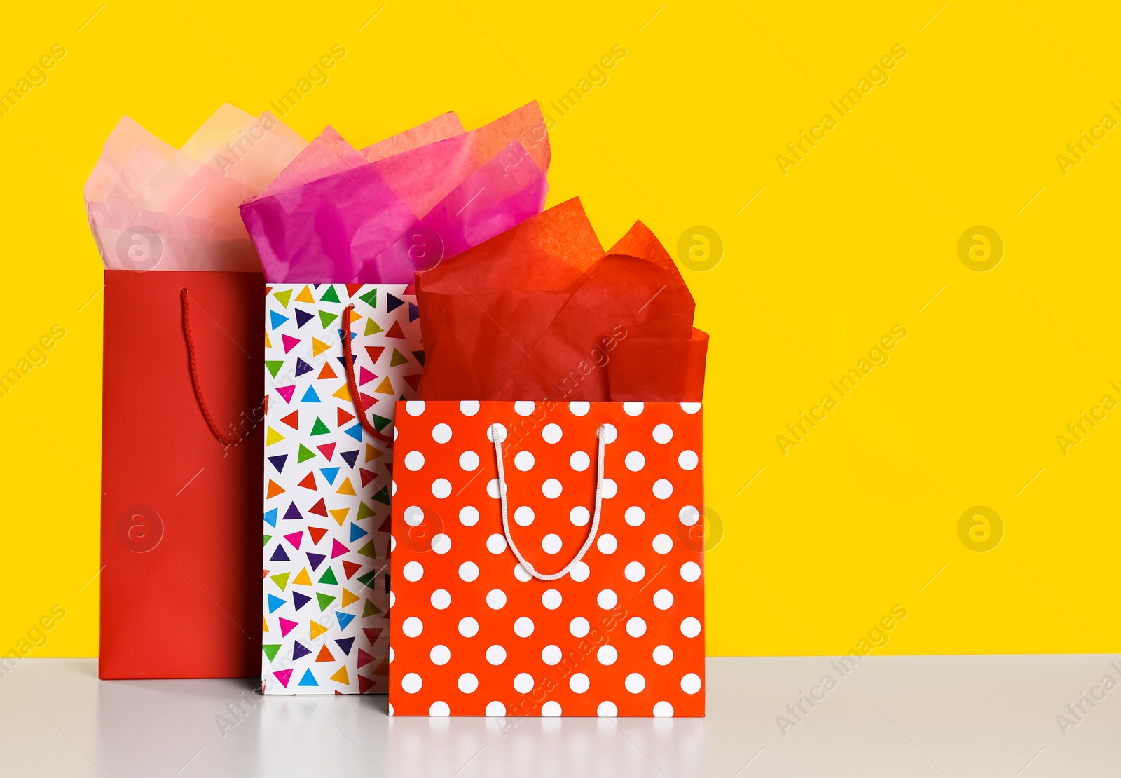 Photo of Shopping bags with paper on yellow background. Space for text