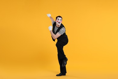 Photo of Funny mime artist posing on orange background