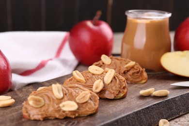 Photo of Pieces of fresh apple with peanut butter on table, closeup