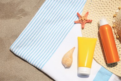 Sunscreens, starfish, seashell and beach accessories on sand, top view with space for text. Sun protection care