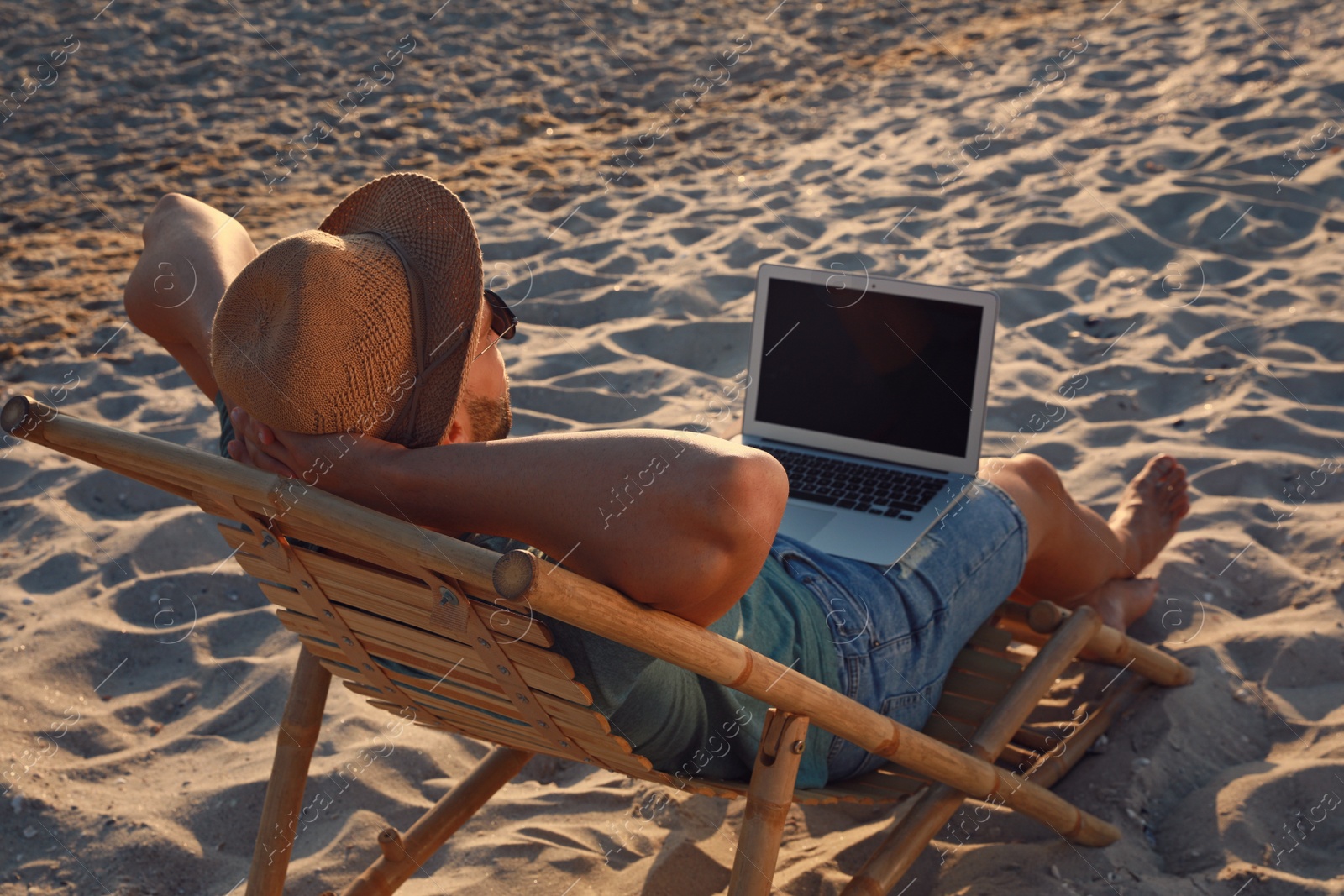 Photo of Man with laptop relaxing in deck chair on beach