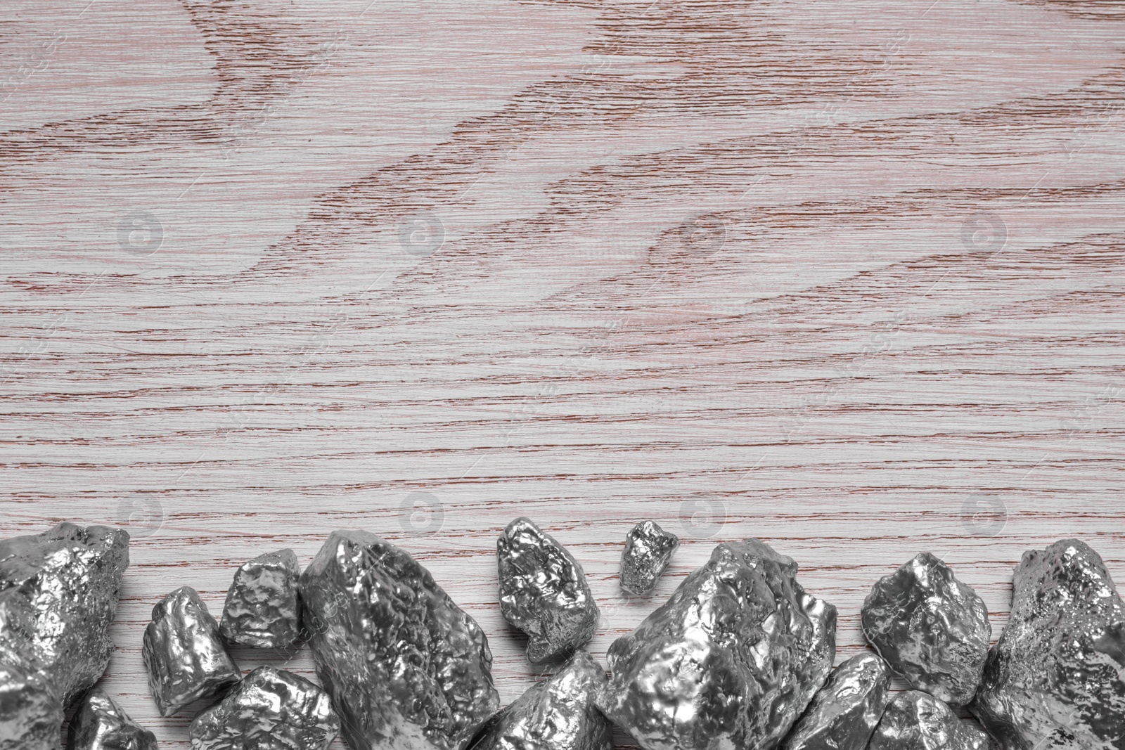 Photo of Pile of silver nuggets on white wooden table, flat lay. Space for text