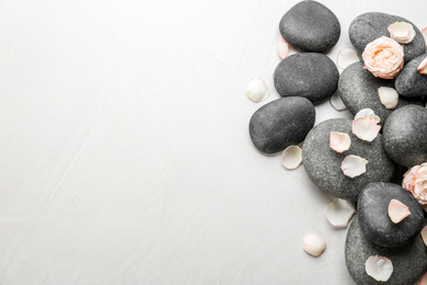 Photo of Stones and flowers on light background, top view with space for text. Zen lifestyle