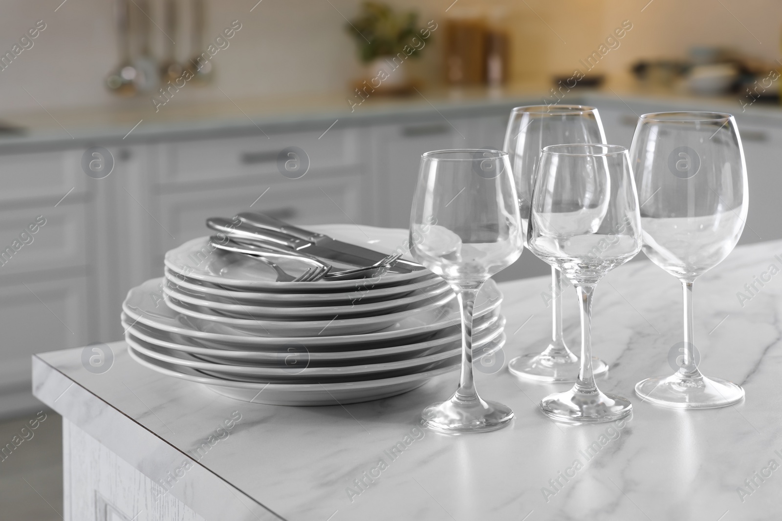 Photo of Different clean dishware, cutlery and glasses on white marble table in kitchen