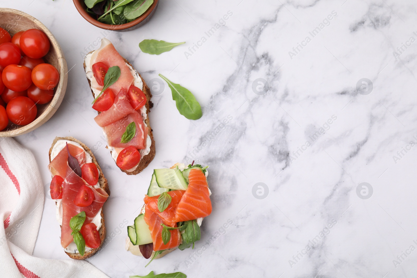 Photo of Flat lay composition with different tasty bruschettas and ingredients on white marble table. Space for text