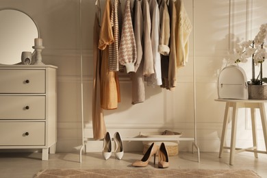 Modern dressing room interior with stylish clothes, shoes and beautiful orchid flowers