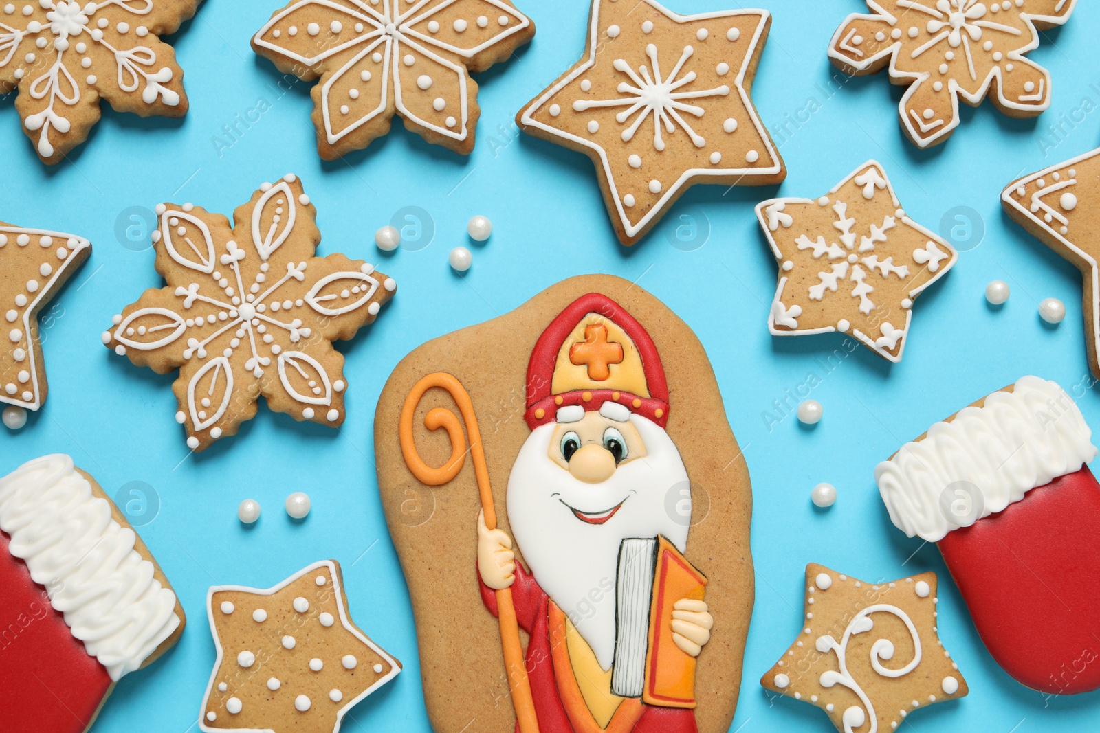 Photo of Tasty gingerbread cookies on light blue background, flat lay. St. Nicholas Day celebration