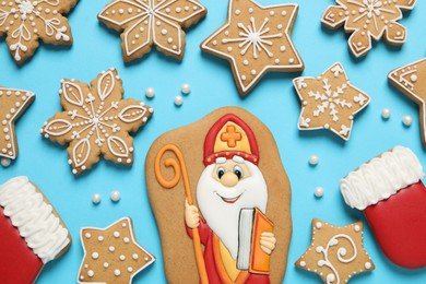 Tasty gingerbread cookies on light blue background, flat lay. St. Nicholas Day celebration