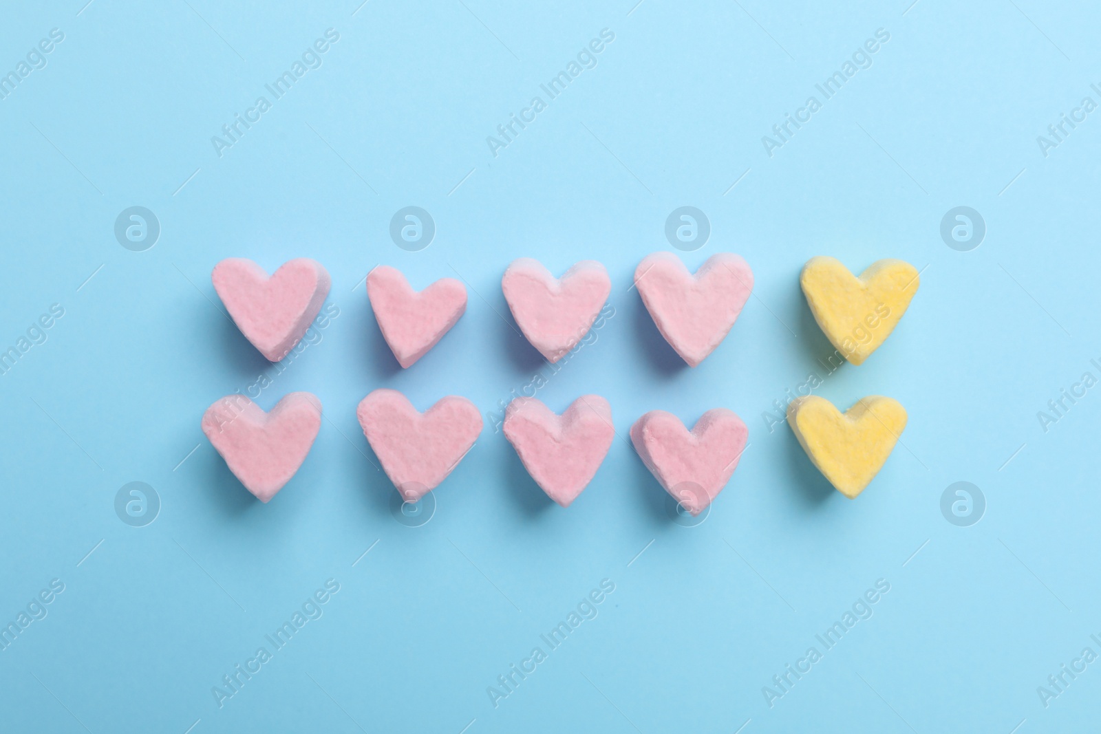 Photo of Flat lay composition with marshmallow hearts on light blue background. Pareto principle concept