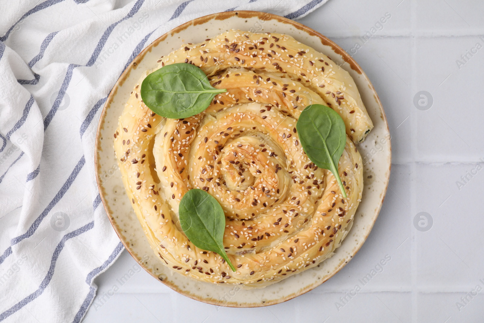 Photo of Delicious puff pastry with spinach on white tiled table, top view