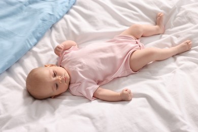 Photo of Cute little baby lying on white sheets