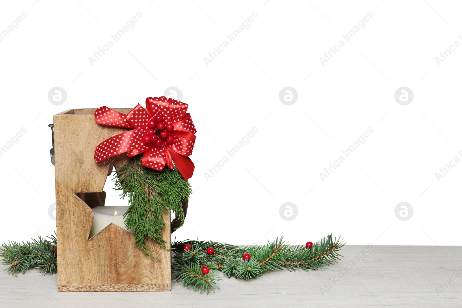 Photo of Wooden Christmas lantern with burning candle and fir branches on table. Space for text