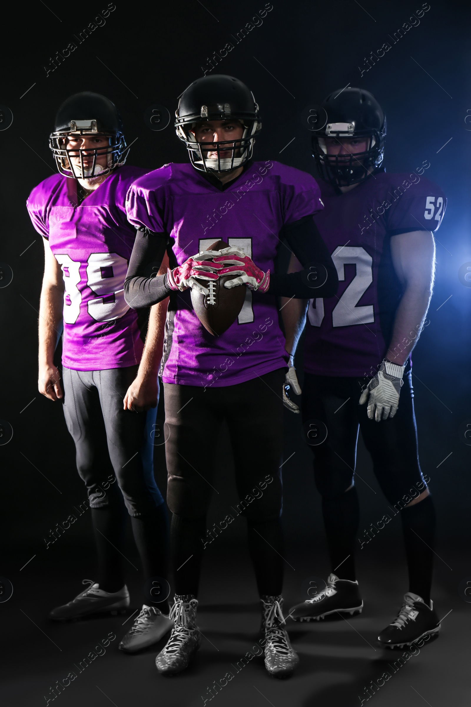 Photo of American football players in uniform on dark background