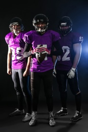 Photo of American football players in uniform on dark background
