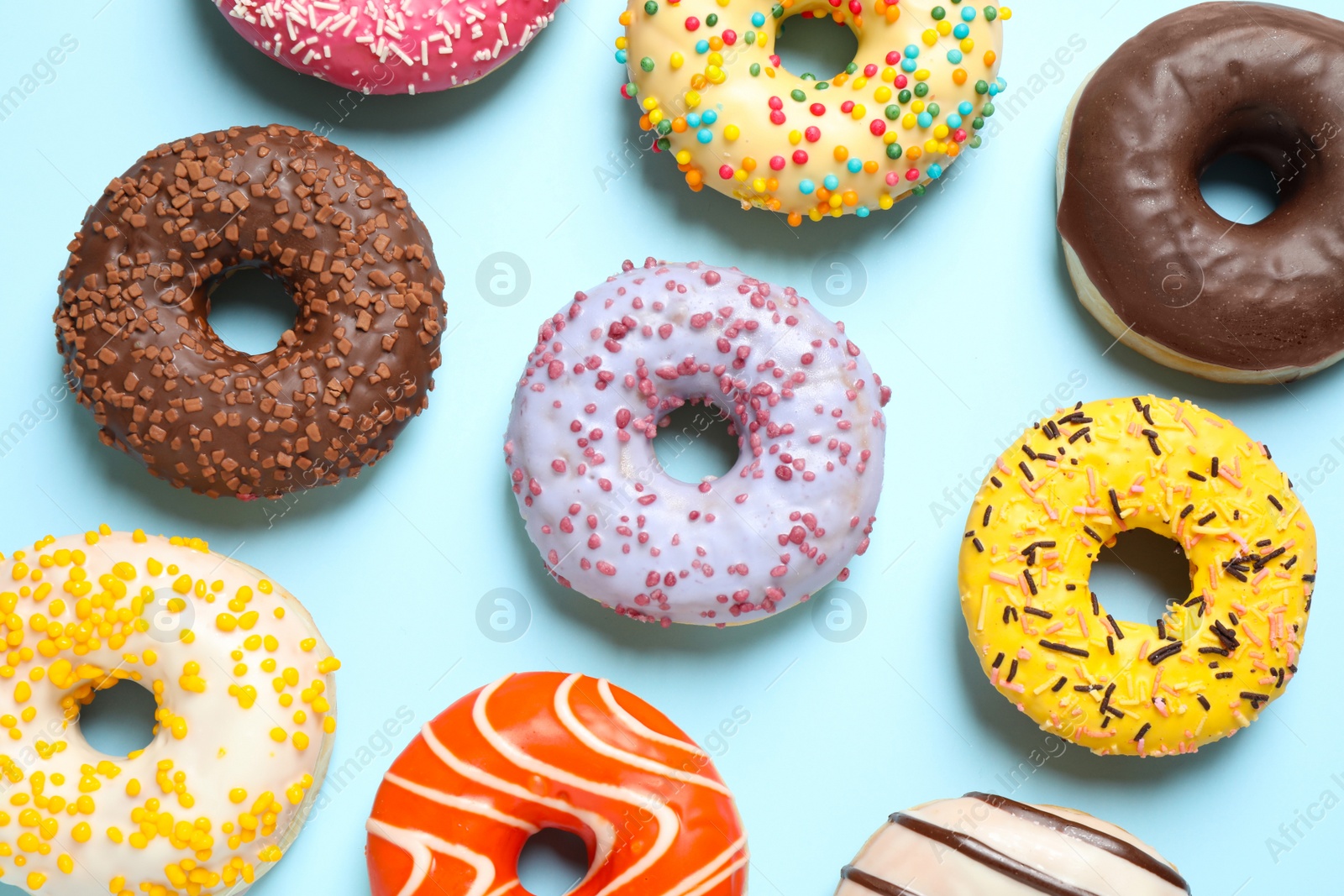 Photo of Delicious glazed donuts on light blue background, flat lay