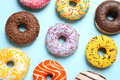 Delicious glazed donuts on light blue background, flat lay