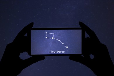 Image of Woman using stargazing app on her phone at night, closeup. Identified stick figure pattern of Little Bear (Ursa Minor) constellation on device screen