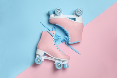 Photo of Pair of stylish quad roller skates on color background, top view