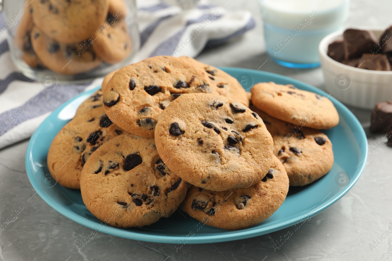 Photo of Plate with delicious chocolate chip cookies on grey marble table, closeup
